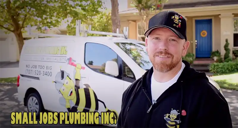 Small Jobs plumber standing in front of service van