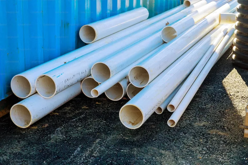 white pipes of different sizes piled on the ground.