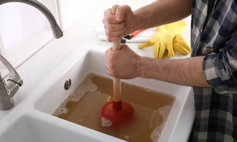 clogged sink with man using a plunger to try and clear it