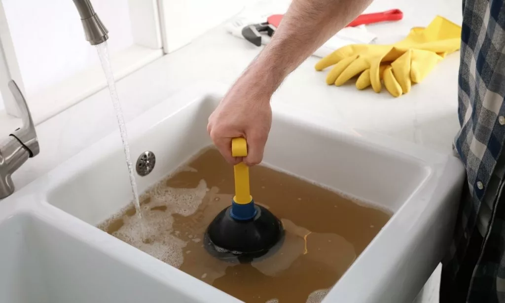 Man using a mini plunger to try and clear a clogged sink