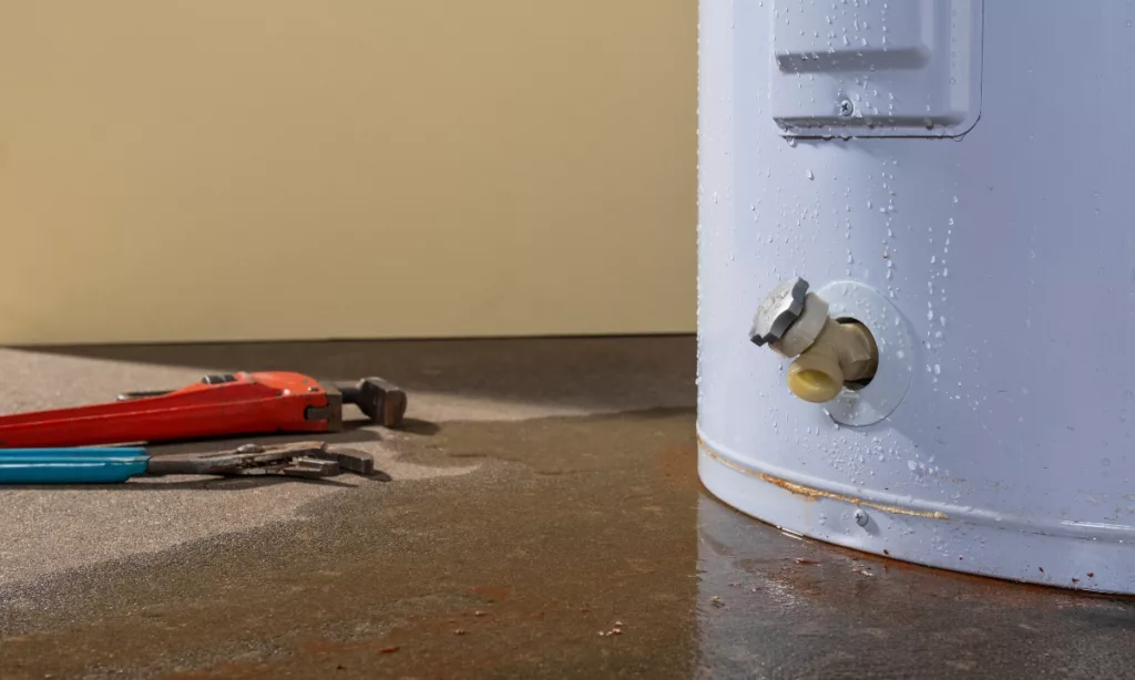 water heater with tools and water on the floor